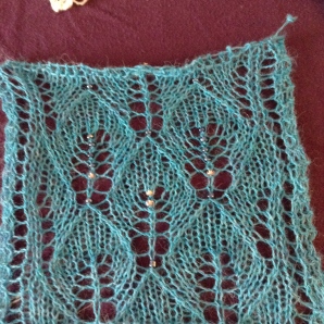 A small blocked swatch of the turquoise shawl, with several "test" beads. I settled on the dark, metallic blue.